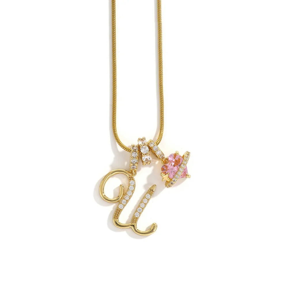 A gold-toned alphabet flower pendant necklace with a delicate chain and pink gemstone detail.