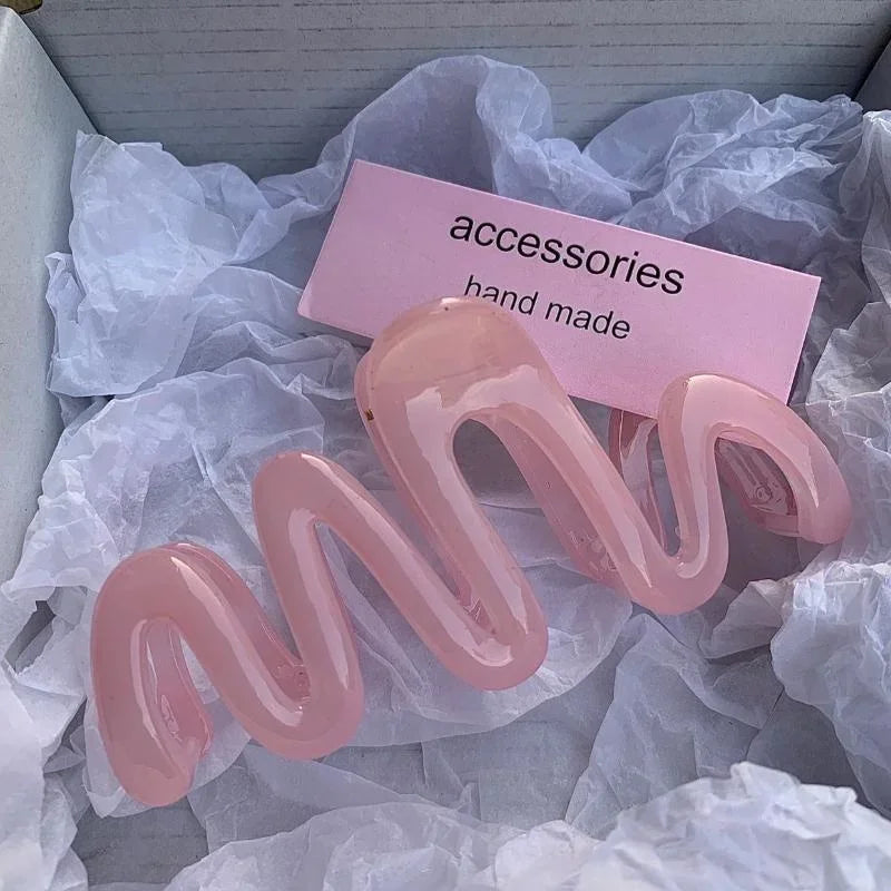 Pinzas para el cabello tipo ola de gel rosa, mostradas sobre papel de seda blanco con etiqueta de accesorios artesanal