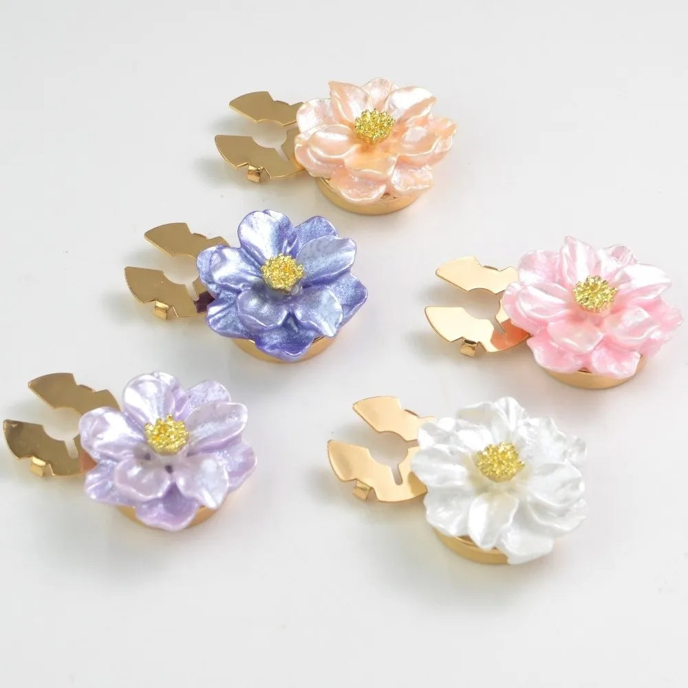 A collection of pearlescent flower button covers in pink, purple, and white on gold-toned metal mounts.