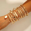 A stack of gold geometric minimalist bracelets worn on a wrist.