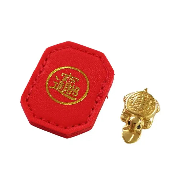 Red felt tag with gold lettering and a gold turtle charm for longevity and financial stability
