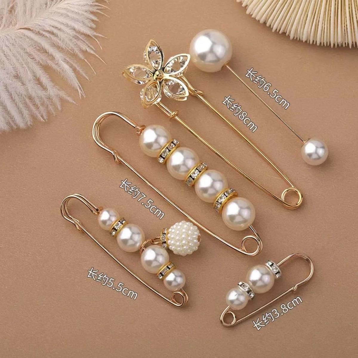 Gold-toned heavy duty pearl safety pins for clothing displayed on a neutral background.