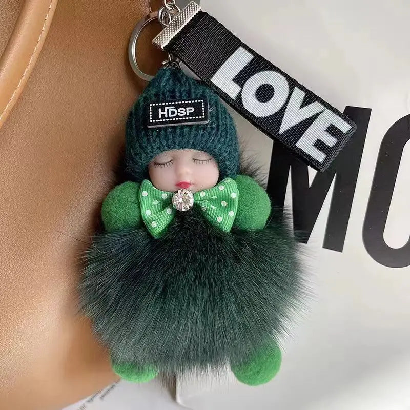 A green knitted plush doll with a pink nose and green fur, attached to a black tag.