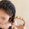A close-up of a woman wearing a brown resin wave toothed headband and a pearl necklace.