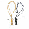 Goldkette mit Totenkopf-Anhänger und dunkler Vogel-Silhouette