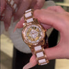Primer plano de un reloj de pulsera de diamante de cuarzo dorado y blanco sostenido por una mano.