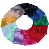 A circular arrangement of satin drawstring jewelry pouches in various colors including black, blue, green, red, purple, and g