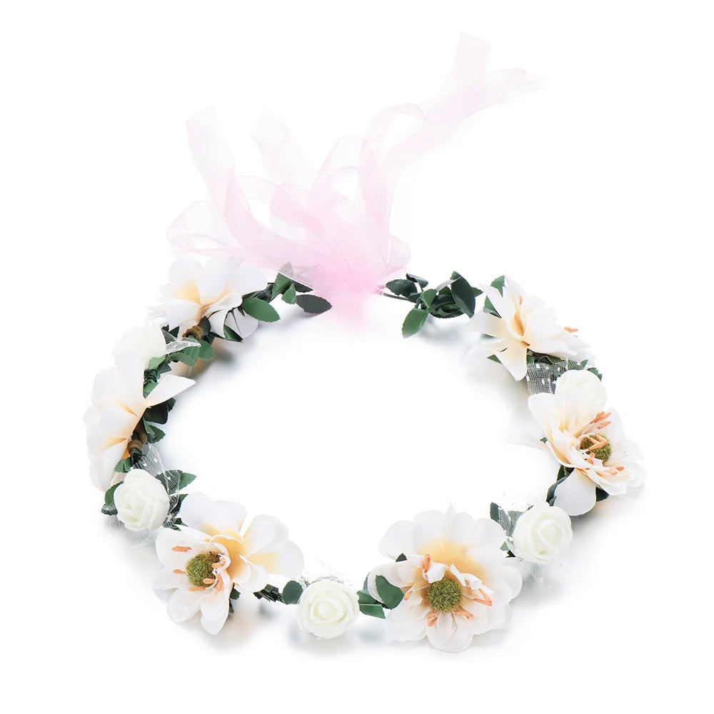 A white and green floral wreath headband with pink sheer ribbons.