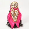 A pink satin silk scarf featuring gold chain detailing tied around a dark hairstyle.