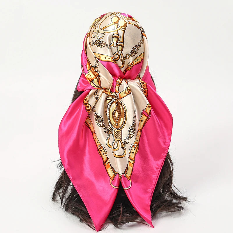 A pink satin silk scarf featuring gold chain detailing tied around a dark hairstyle.