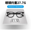 A pair of black reading glasses placed on a white weighing scale, showing the weight measurement 27.7G.