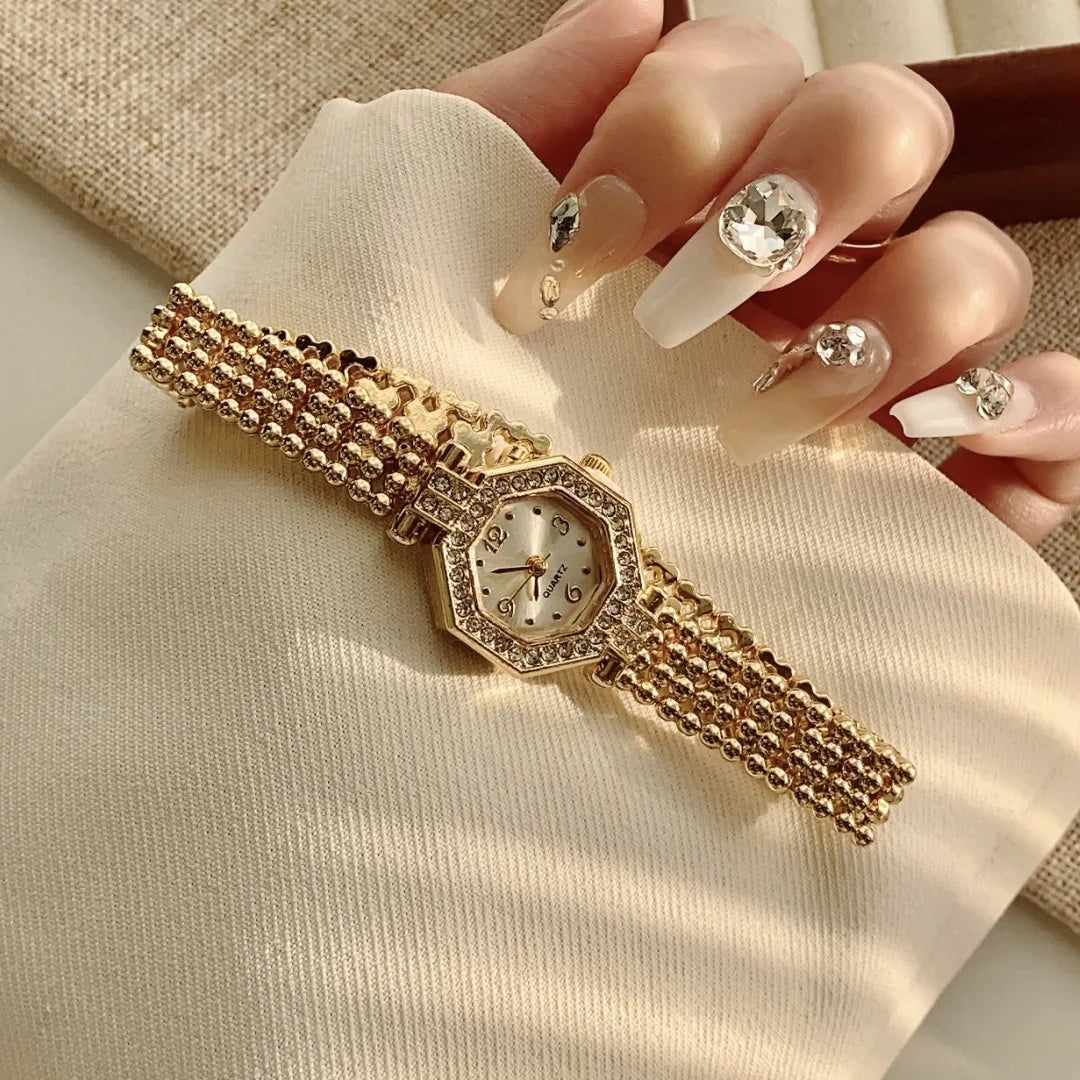 A close-up of a gold-toned quartz fashion wristwatch with a diamond-encrusted band and clear crystal face, worn on a hand aga
