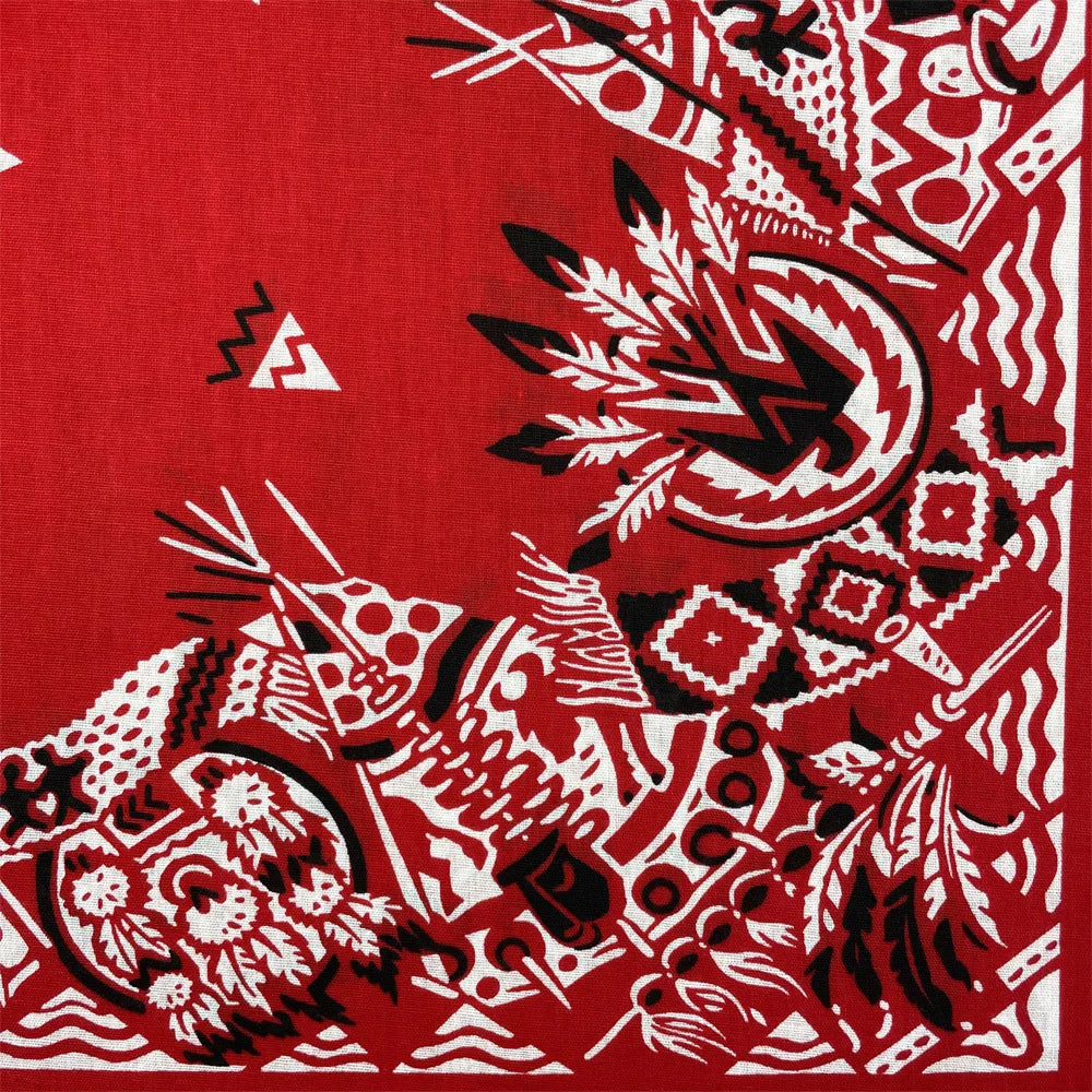 A close-up of a red textile featuring black and white geometric tribal patterns.