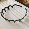 Black resin wave toothed headband for women displayed on a white striped surface.