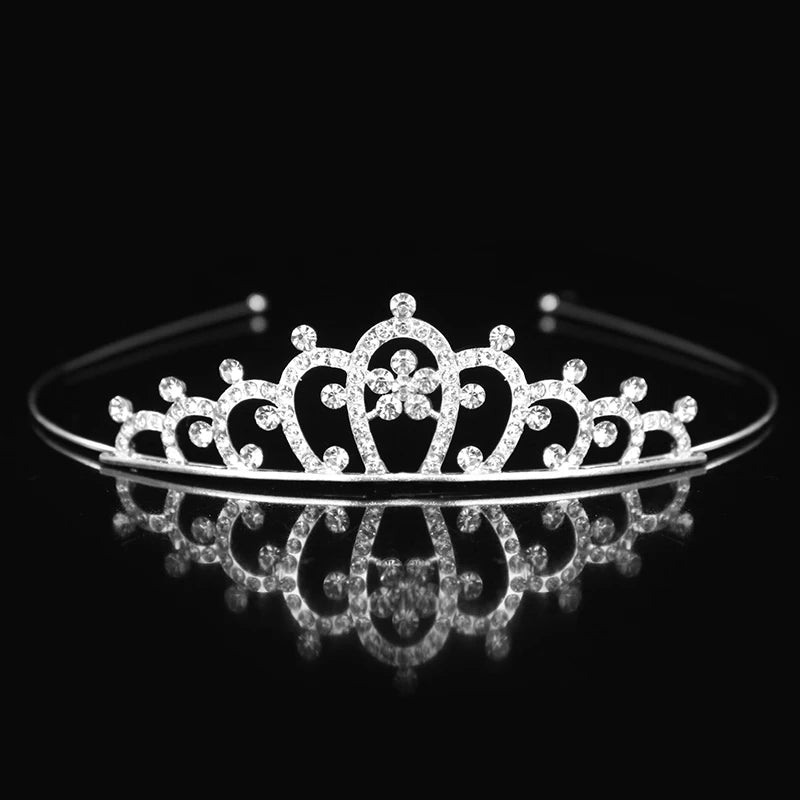 Tiara y corona de princesa de cristal brillante para el cabello, exhibidas en una superficie reflectante.