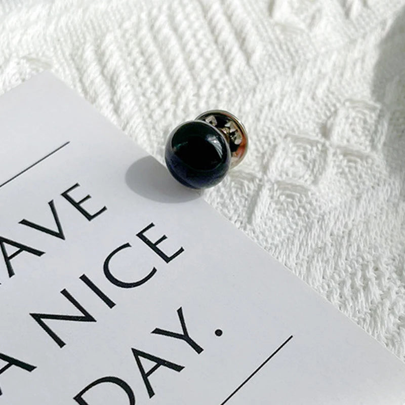 A close-up of a gold-toned pearl button set resting on a white card against a textured white background.