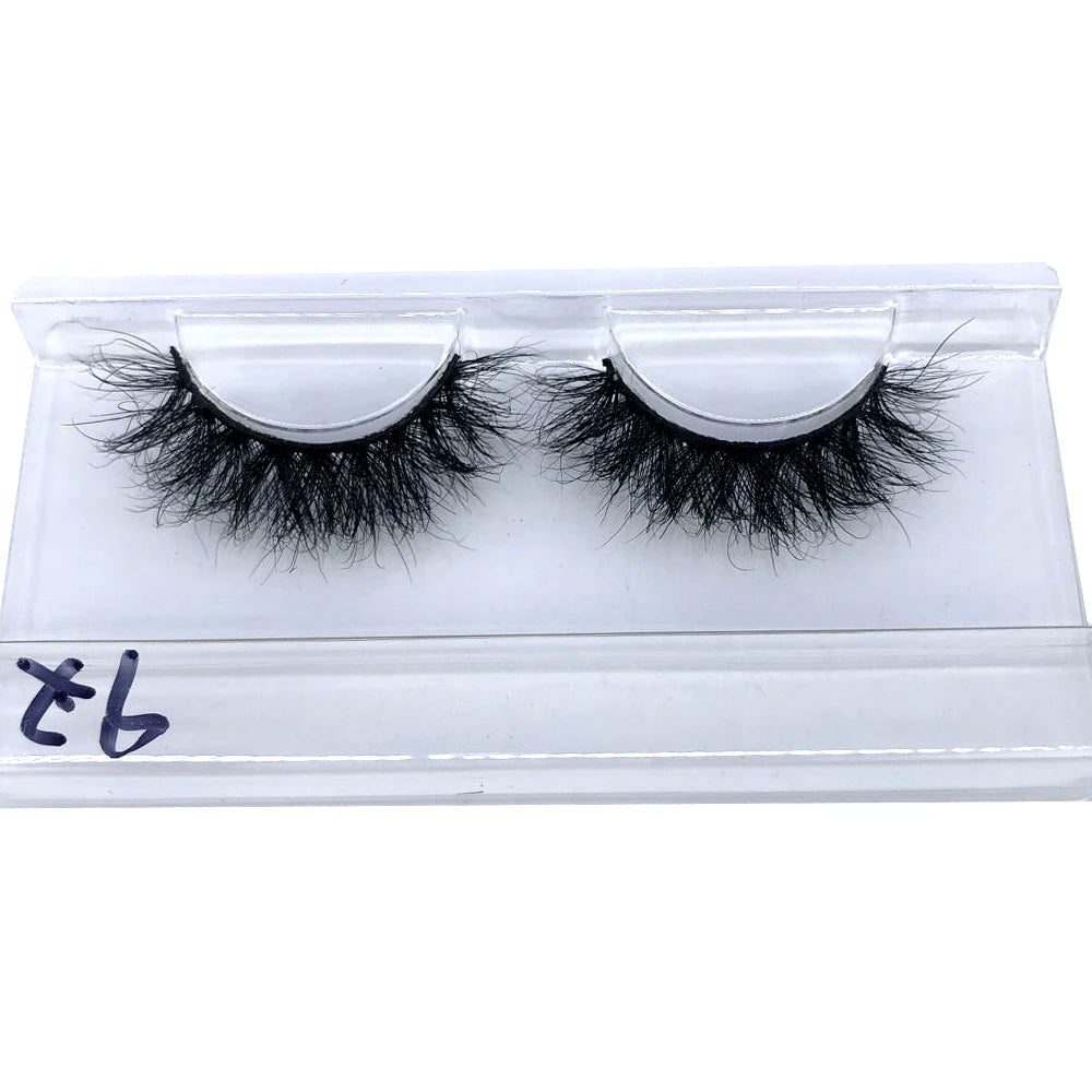 A pair of black mink false eyelashes displayed on a clear plastic tray.