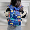 A blue backpack featuring a cute dinosaur and unicorn pattern worn by a person.