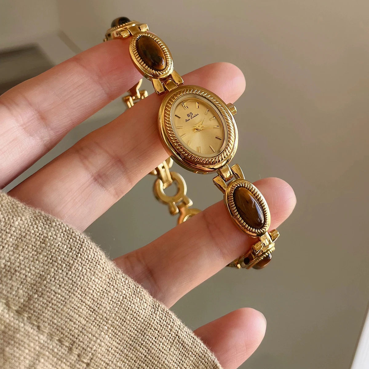 Gros plan d'une élégante montre-bracelet en quartz dorée avec un cadran rond et des perles ovales de couleur jade sur le brac