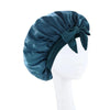 A dark teal satin wide-brimmed hair wrap headscarf tied in a bow displayed on a white mannequin.