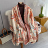 A beige and coral plaid cashmere scarf and shawl wrap draped over a white chair.