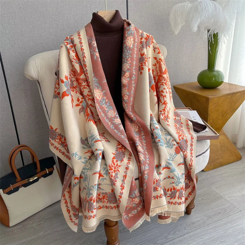 A beige and coral plaid cashmere scarf and shawl wrap draped over a white chair.
