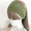 A model is wearing a olive green knitted hair band on her head.