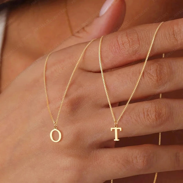 A close-up of a hand wearing a delicate gold initial letter necklace with the letter O and T.
