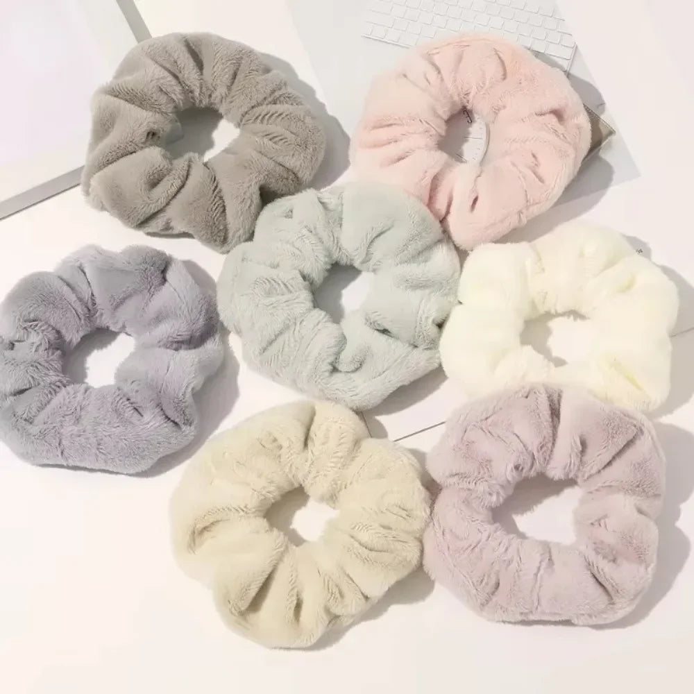 Collection de pinces à cheveux en tricot doux dans diverses nuances de gris, rose et crème, disposées sur une surface blanche