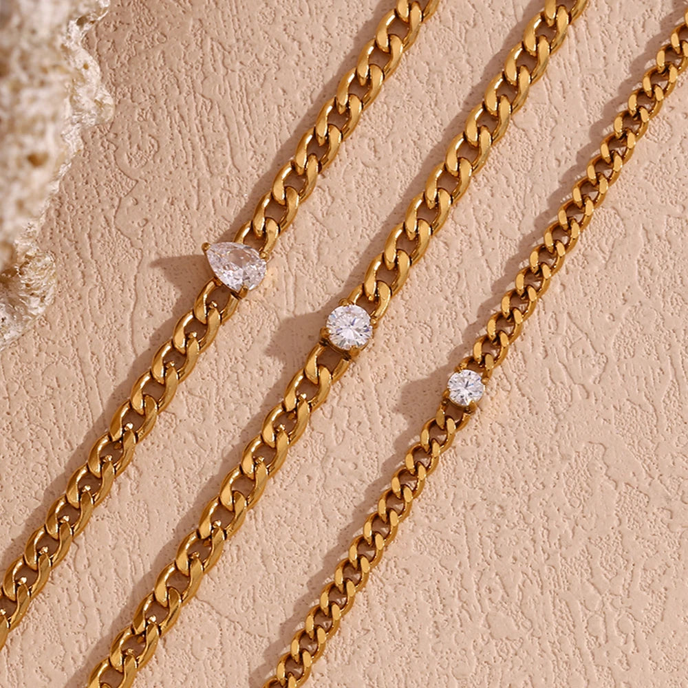 Gold chain bracelet featuring round water drop zircon charms on a beige background.