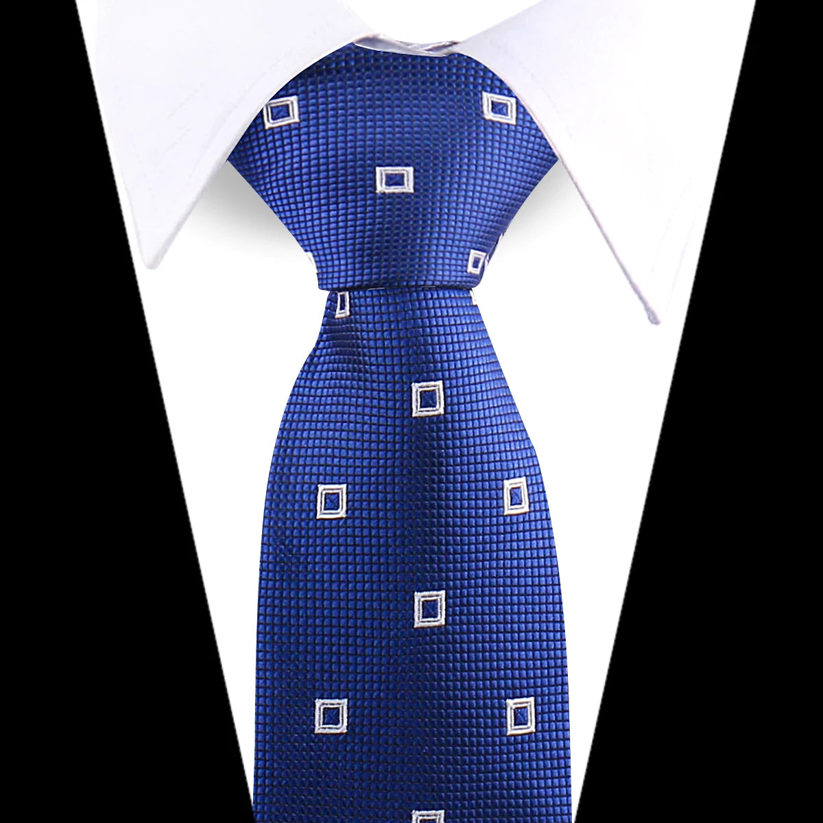 A close-up of a royal blue patterned silk necktie with white square accents against a white shirt.