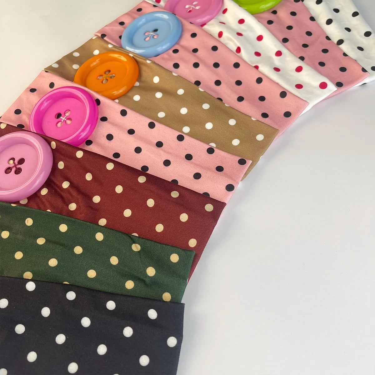 A collection of vintage polka dot fabric headbands in various shades of pink, green, and brown.