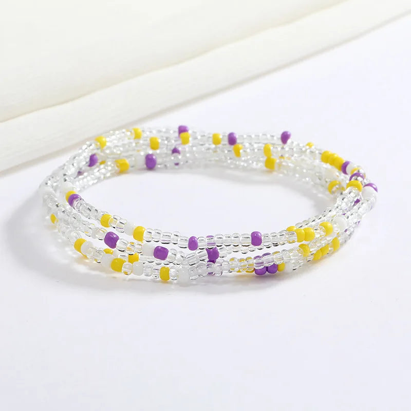 Cadena corporal de cuentas flexible y transparente con pequeñas cuentas moradas y amarillas.