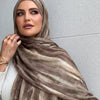 Una mujer vistiendo un elegante pañuelo de hijab de rayas marrón y beige de algodón rayón, drapeado alrededor de su cuello.