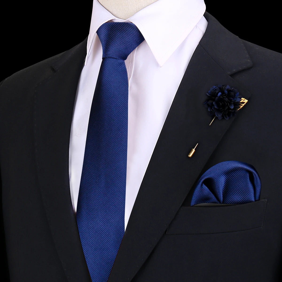 Chaqueta de traje negra con camisa blanca, corbata de seda azul y pañuelo de bolsillo y prendedor de seda azul oscuro.