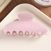 A pink striped silicone hair clip is displayed on a white plate.