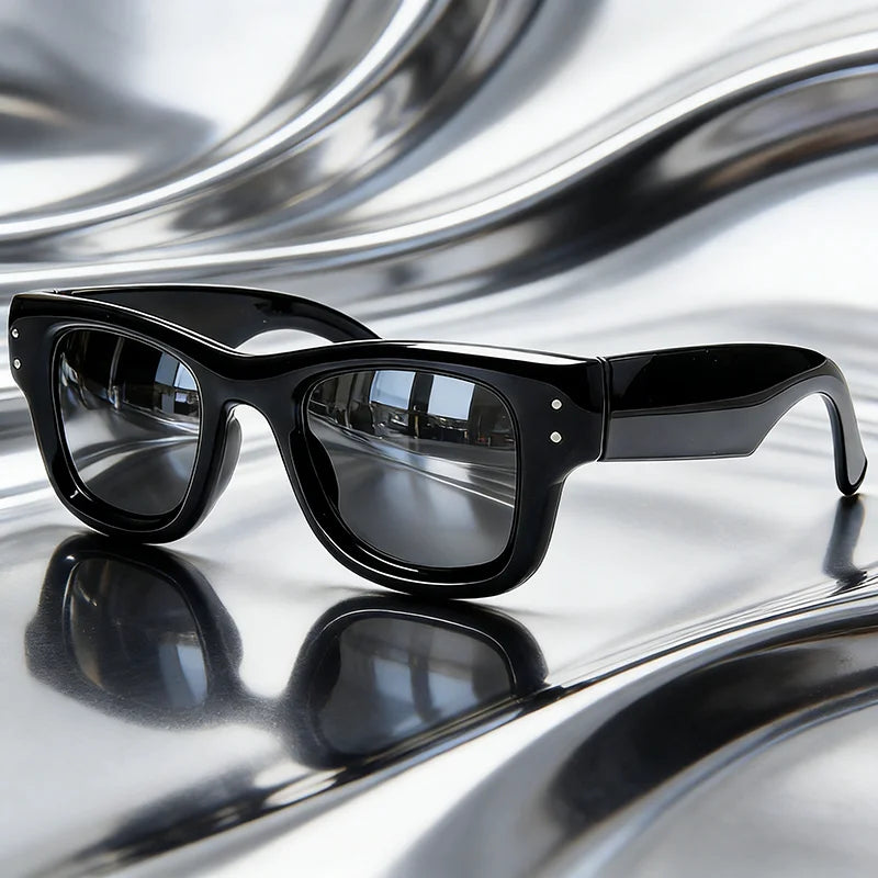 Black classic puffer square sunglasses resting on a reflective, wavy surface.