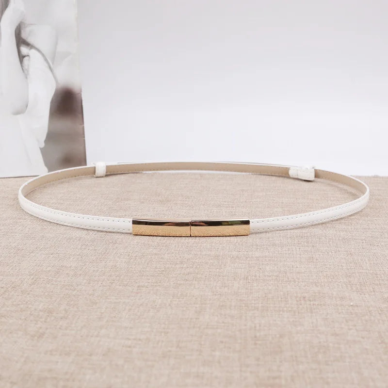 Beiger Leder-Slim-Gürtel mit goldener Schnalle auf hellem Stoff