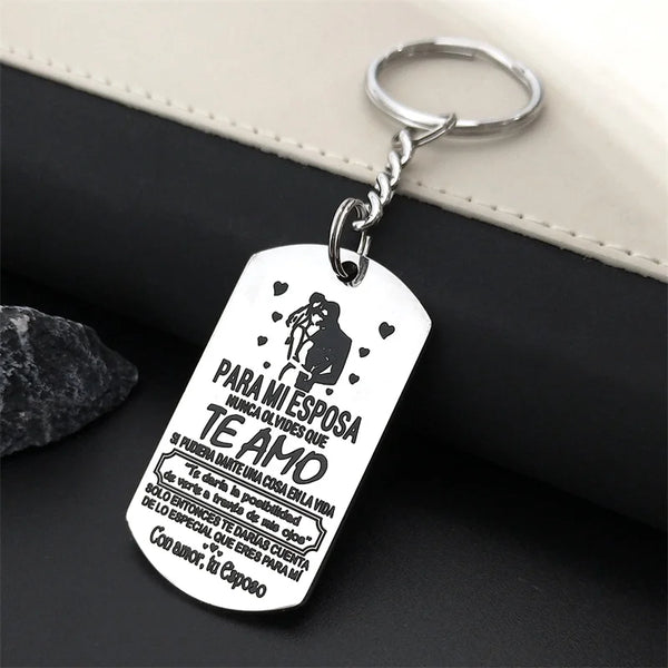 A silver stainless steel tag with a silhouette of a couple and text in Spanish hangs from a keyring.