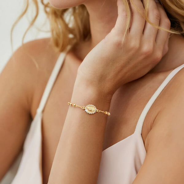 A close-up of a woman's wrist wearing an 18K gold plated rosary bracelet.