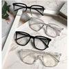 A collection of black and clear framed anti-blue light spectacles displayed on a white marble surface.