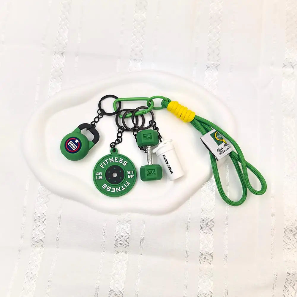 A set of five green fitness keychains and weightlifting accessories with yellow cord displayed on a white plate.