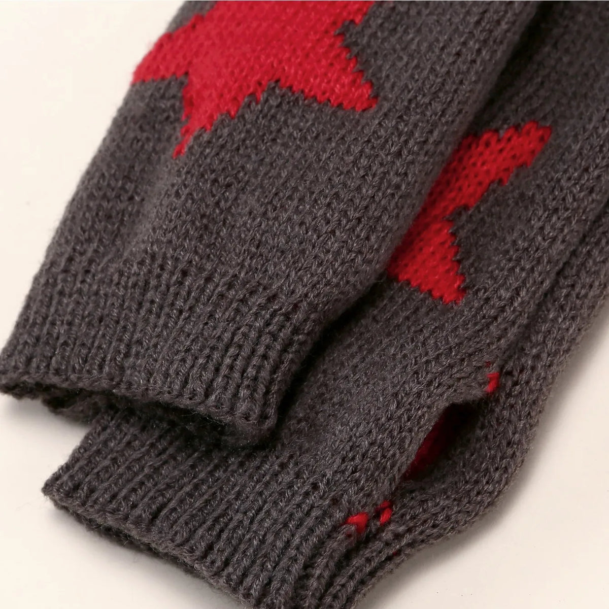 A pair of gray knitted half finger gloves featuring a red maple leaf pattern.
