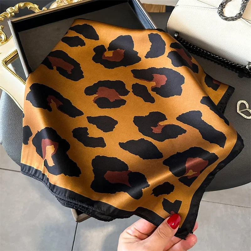 Ein Stück luxuriöser Leopardenmuster-Satinstoff, drapiert auf einer dunklen Oberfläche.