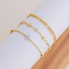 A set of handmade gold-colored crystal cross anklets worn on a wrist.