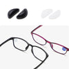 A pair of eyeglasses with silicone nose pads shown in black and pink frames, along with separate black and white nose pads.