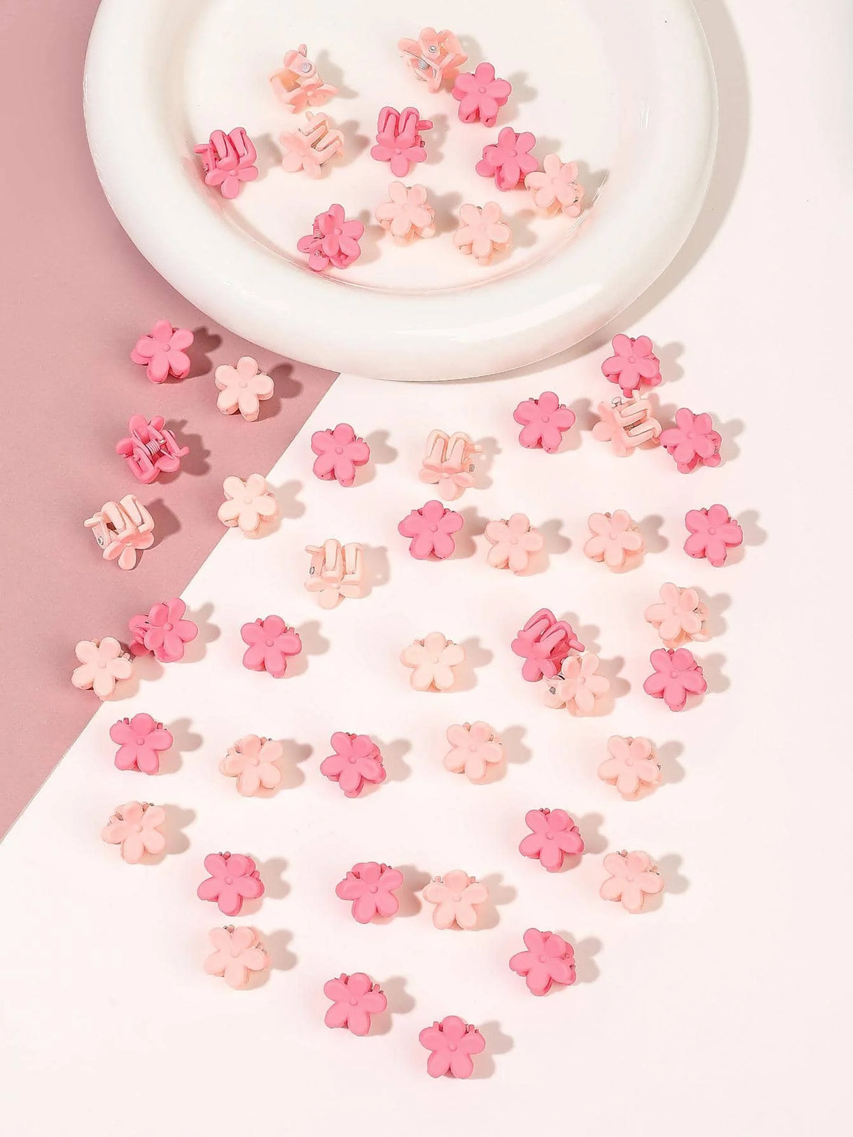 A collection of pink and coral mini flower hair clips arranged on a white plate.