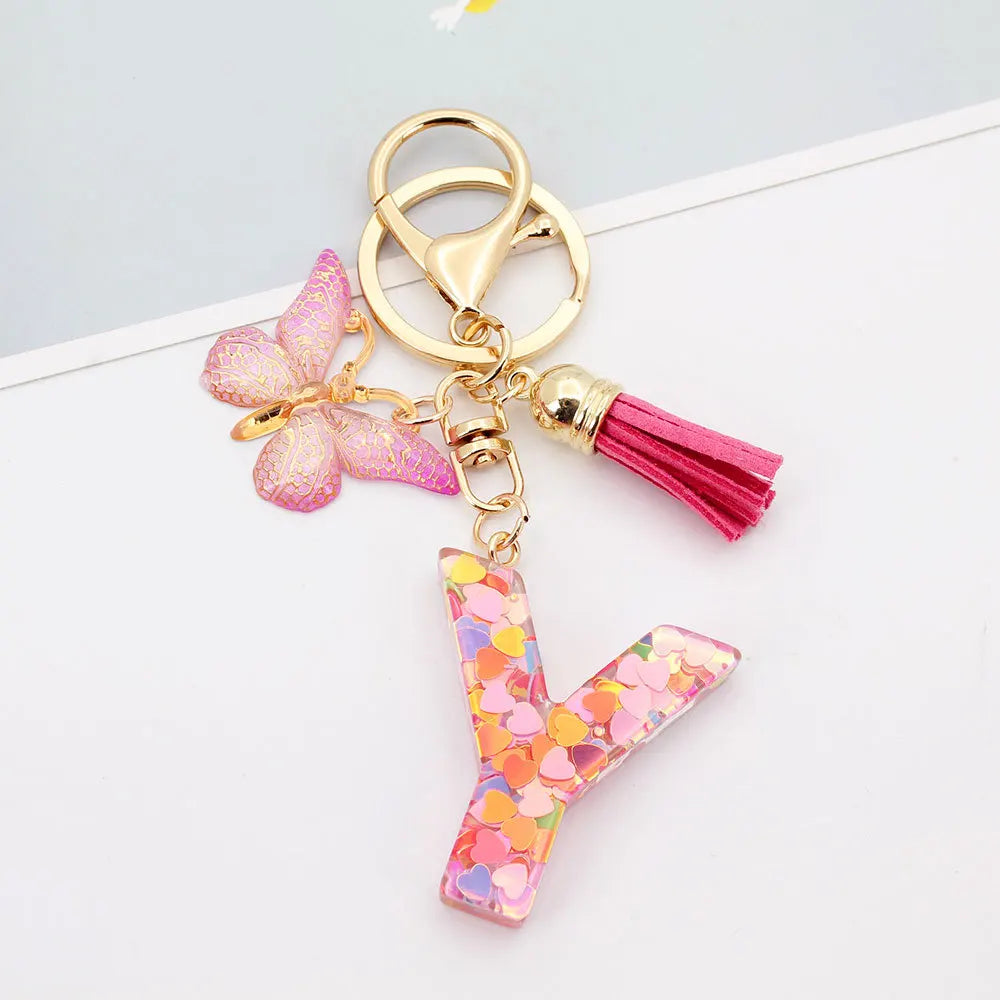 Gold acrylic letter keychain shaped like the letter Y with a pink butterfly and a magenta tassel