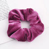 A close-up of a deep purple velvet scrunchie with gathered fabric texture.