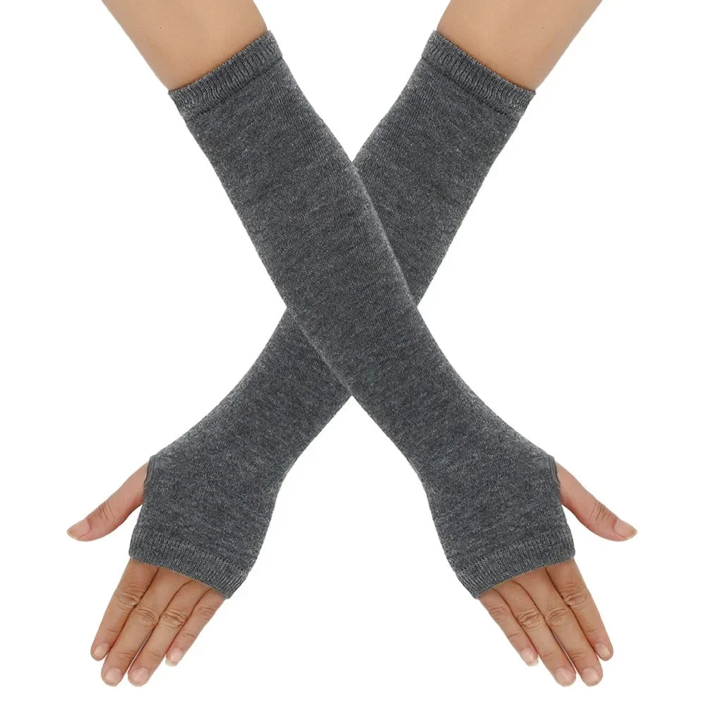 A pair of gray knitted fingerless gloves crossed on a person's hands.